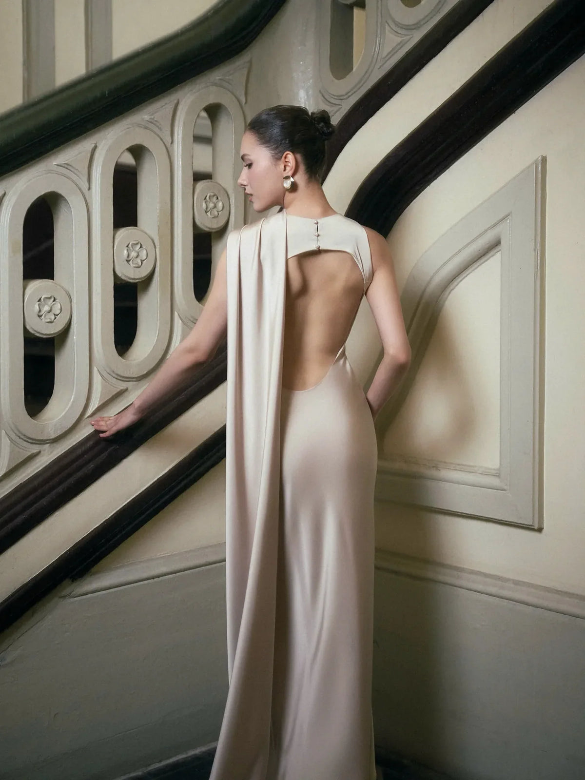 Off-white satin gown back with dramatic open design and flowing cape detail from the dress collection